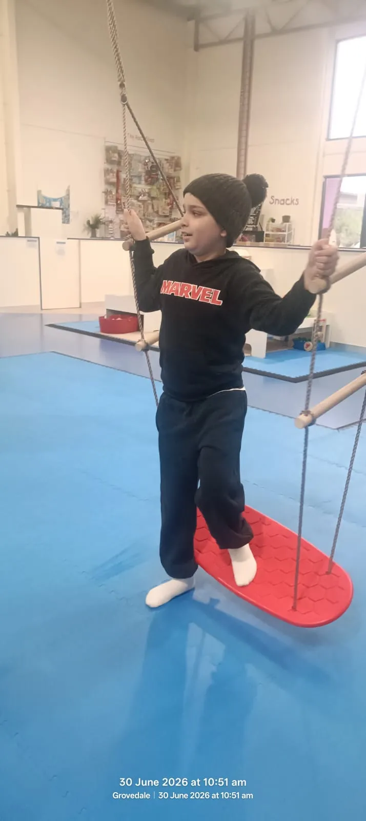 A participant balancing on a suspended sensory swing board during an OT session