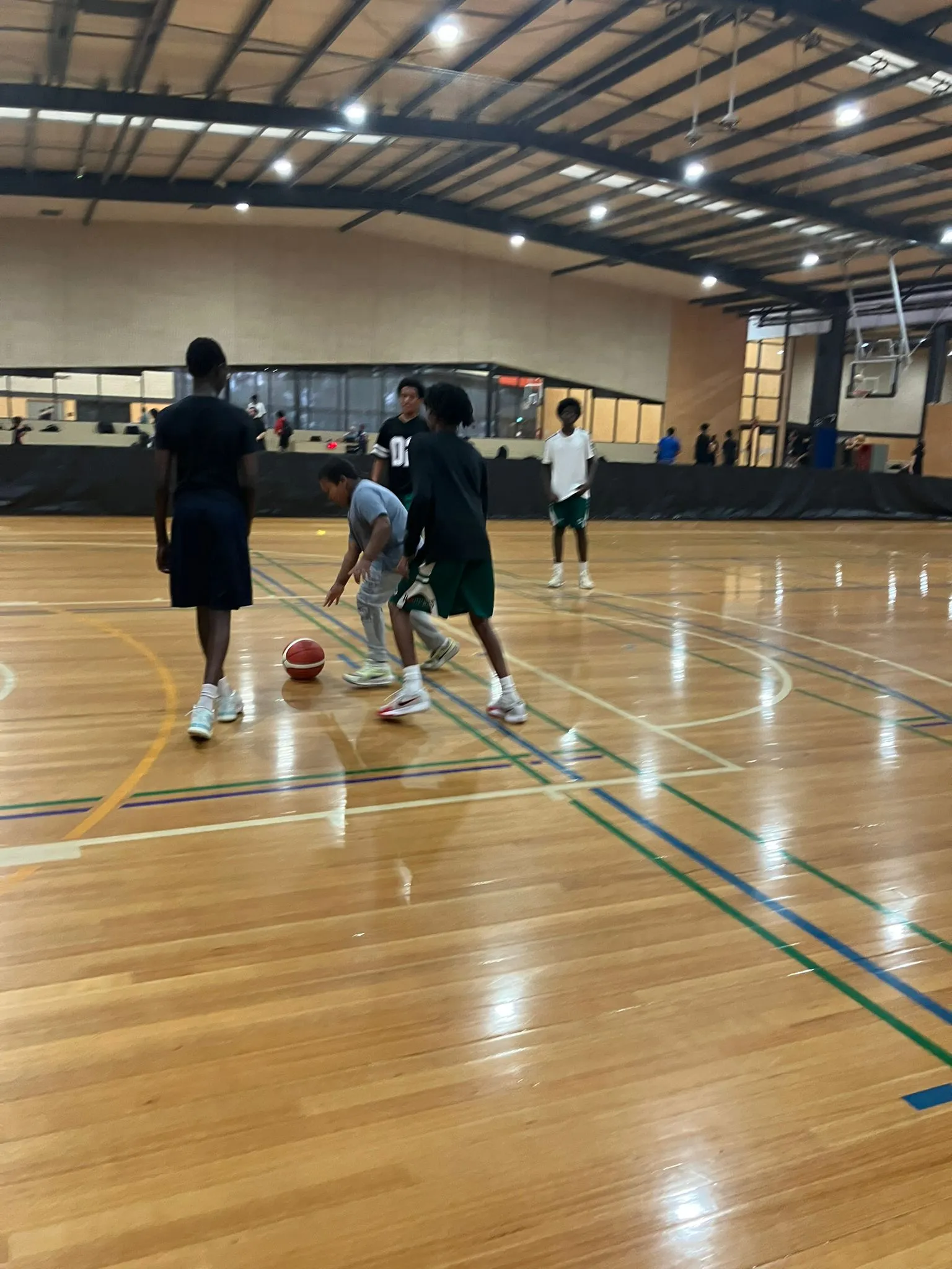 A participant playing basketball on an indoor court during a recreation session