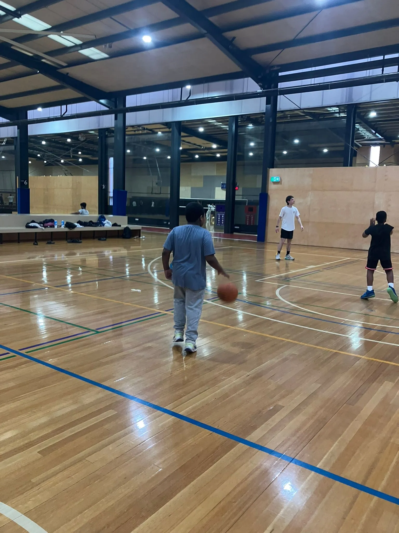 Participants shooting hoops together during an indoor basketball session