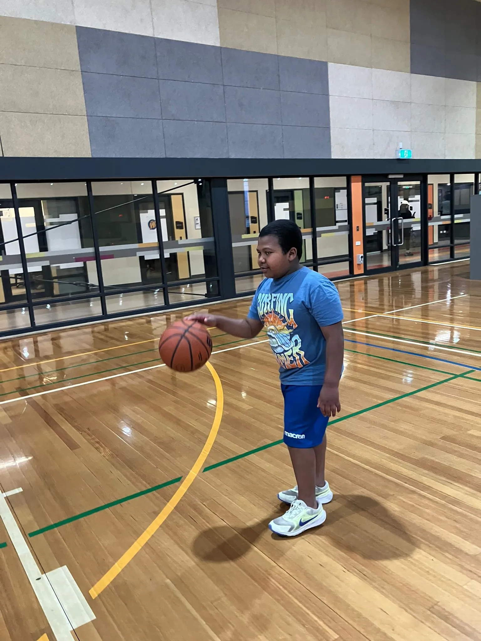 A participant playing basketball on an indoor court during a recreation session