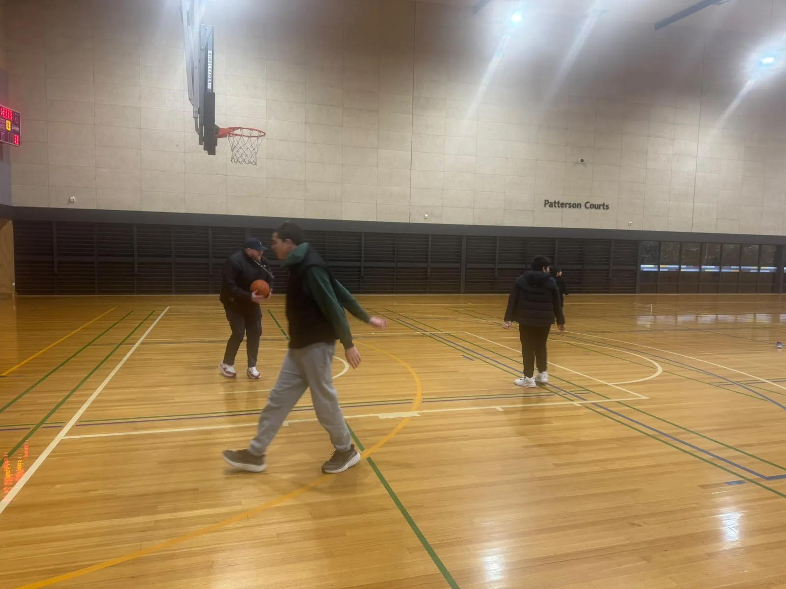 Participants shooting hoops together during an indoor basketball session