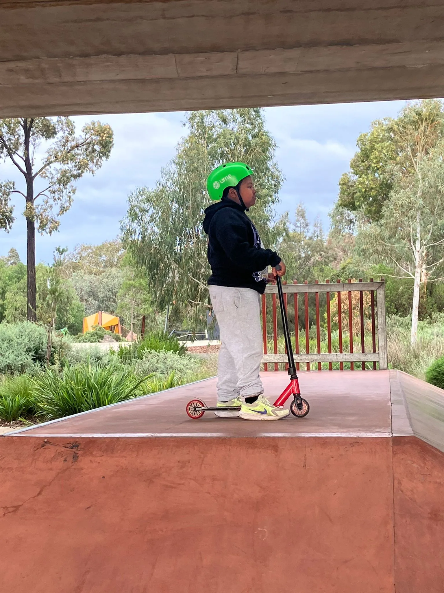 A participant riding a scooter at a skate park during an outdoor recreation outing